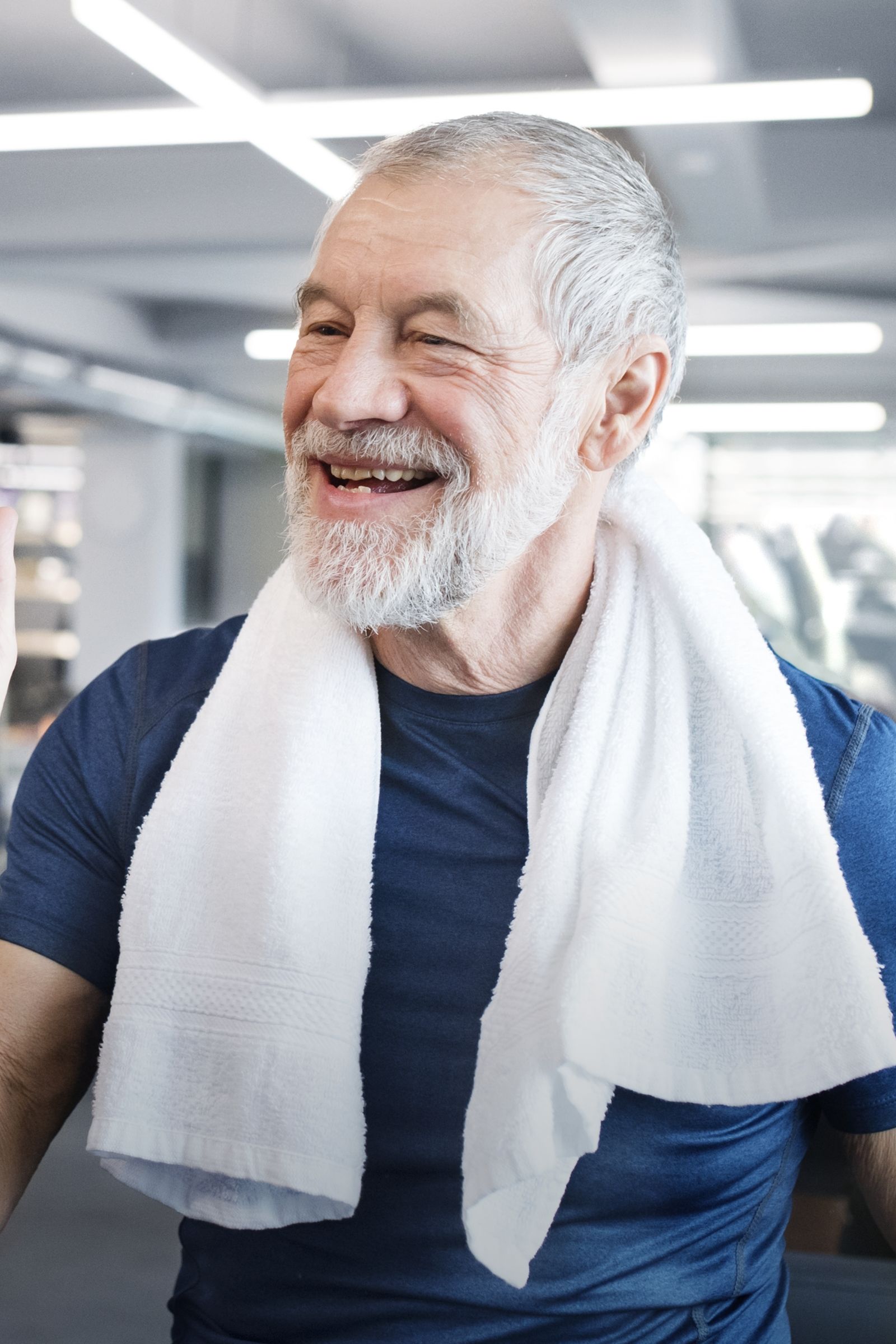 Older adult smiles with a towel around his neck after a workout