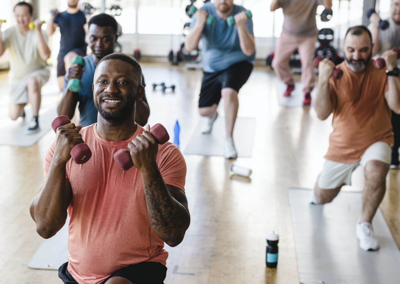 Man leads exercise class of other men.