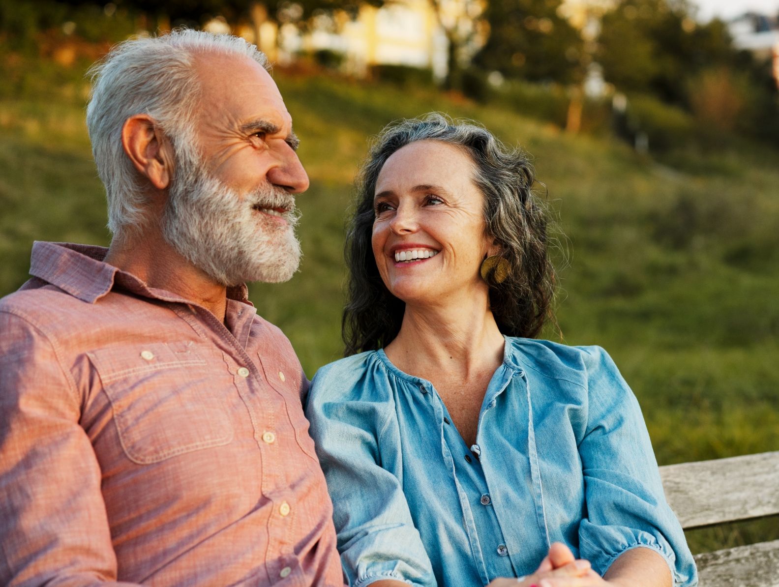 Older Adult couple smiles on park bench